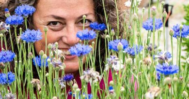 Michele Vaughan peers through a group of flowers