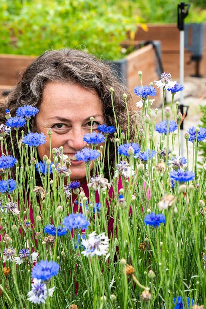 Michele Vaughan peers through a group of flowers. 