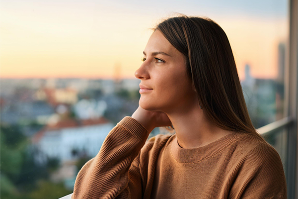 A woman leans on a railing, looking out into the city. 