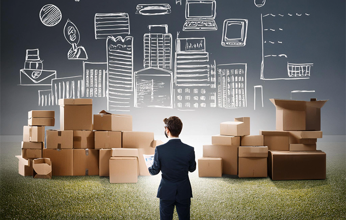 Man standing in front of boxes in a field with drawings of business processes and computers in the sky.