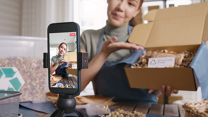 Woman selling goods on social media using phone to record video.