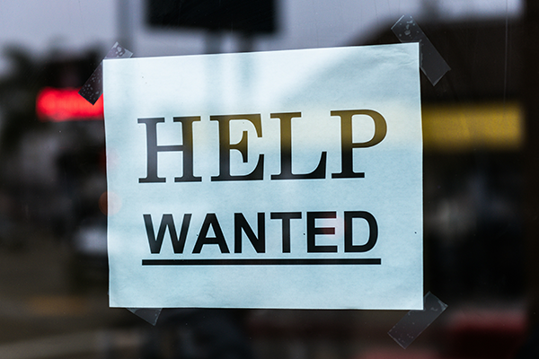 Help Wanted sign taped to window.